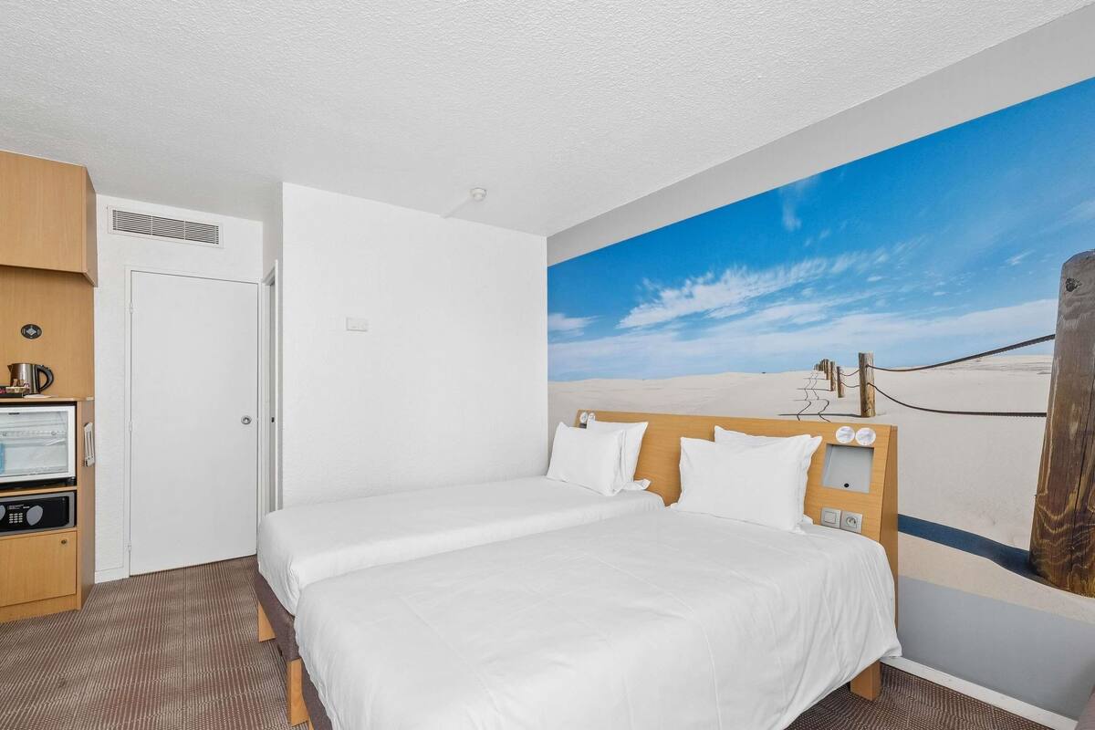 A hotel room with a bed, a microwave, and a door.