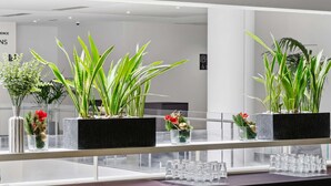 Un intérieur moderne avec des plantes en pot sur un comptoir, une rambarde en verre et un panneau dans le fond.