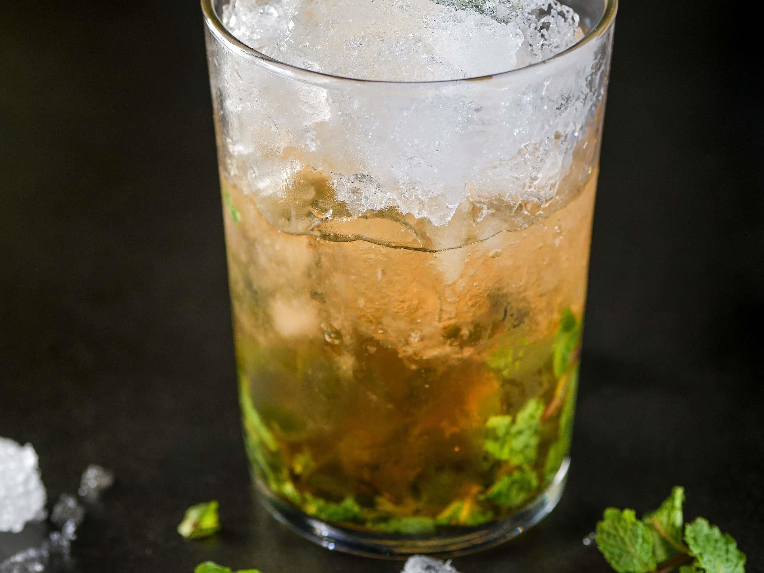 A glass with ice and a dark background.