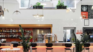 A bar area with a counter, bar stools, and a variety of bottles. - Novotel Paris Est Centre De Conference (Bagnolet)