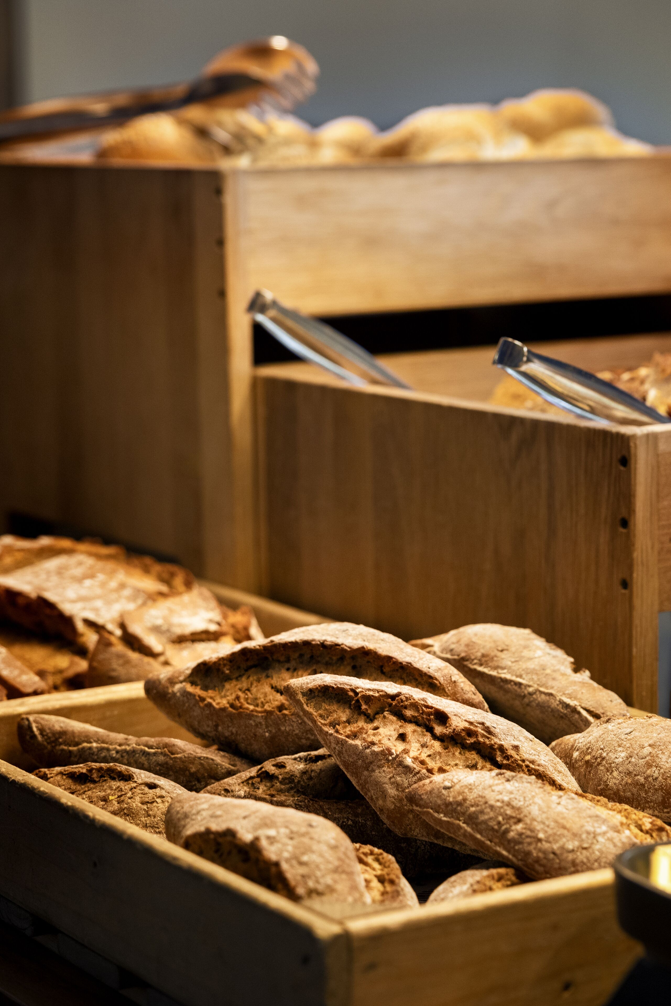 A wooden bread display with various types of bread.