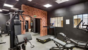 A gym with exercise equipment, a brick wall, and a window.