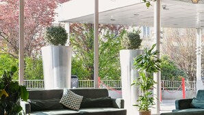 Un espace extérieur moderne aménagé avec un canapé, des tables rondes et des plantes en pot.