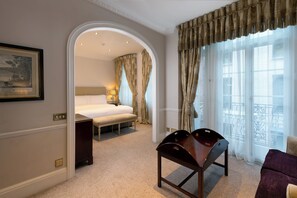 A hotel room with a bed, a desk, a chair, a balcony with a railing, and a framed picture on the wall. - Dukes London (London)
