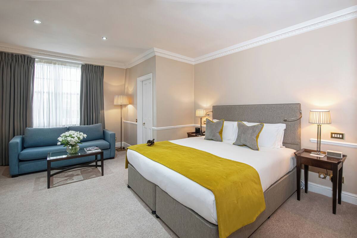 Une chambre d’hôtel avec un grand lit, un canapé, une table de chevet et une lampe.