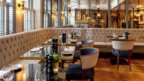 A restaurant with a high ceiling, large windows, and a seating area with tables and chairs. - Dukes London (London)