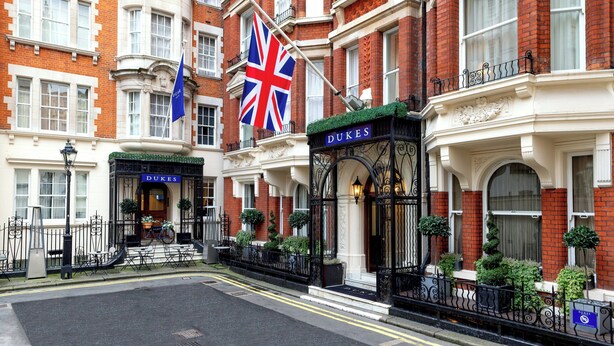 A historic building with a prominent 'DUKES' sign, a British flag, and a traditional entrance with steps and a gate. - Dukes London (London)
