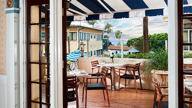 Un patio exterior con una zona de estar cubierta, vistas de los edificios circundantes y suelo de baldosas.