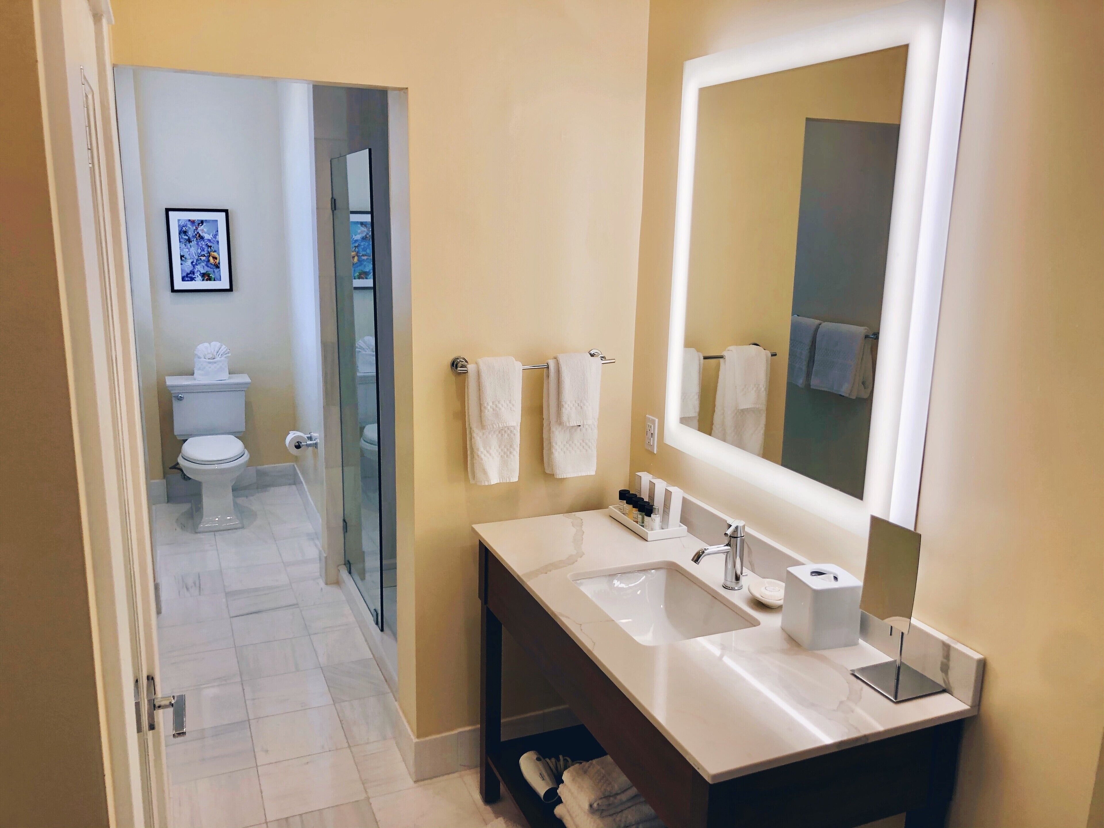 Un baño moderno con un espejo grande, un lavabo blanco y una cabina de ducha de vidrio.