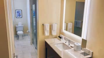 Un baño moderno con un espejo grande, un lavabo blanco y una cabina de ducha de vidrio.