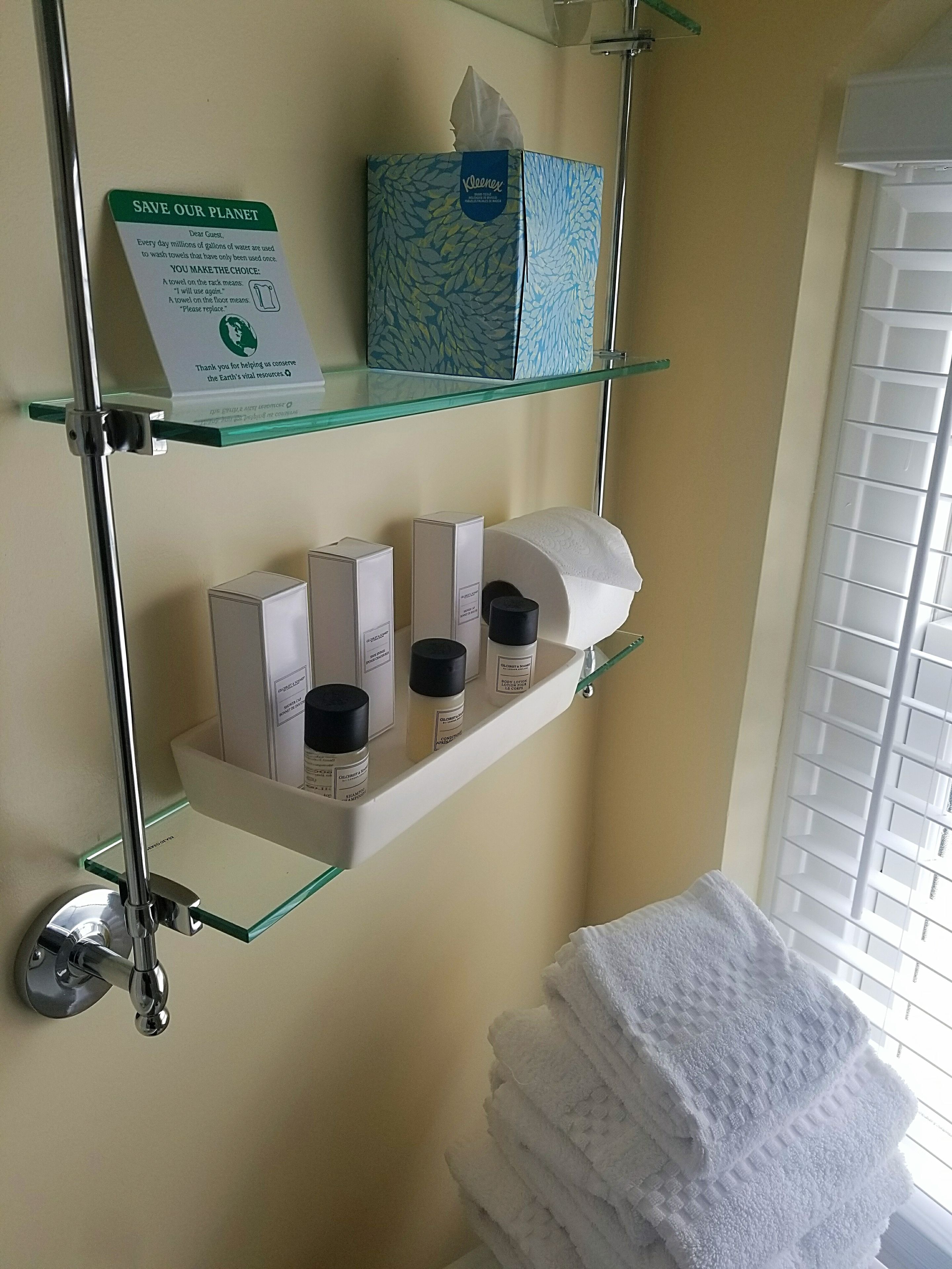 Une salle de bain équipée d’un porte-serviettes, d’une boîte à mouchoirs et de produits de toilette rangés sur des étagères.