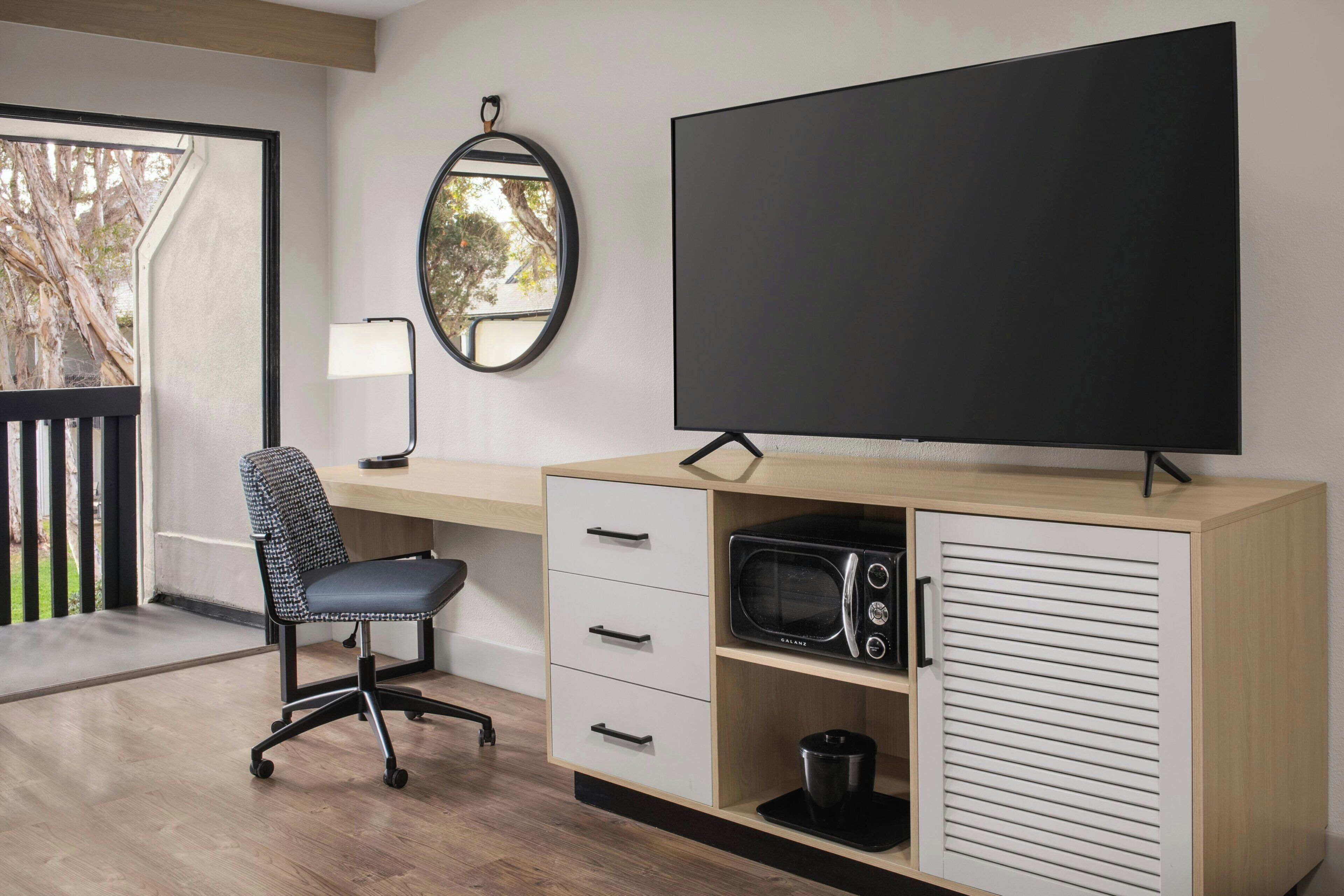 A modern office space with a desk, chair, and a large flat-screen TV.