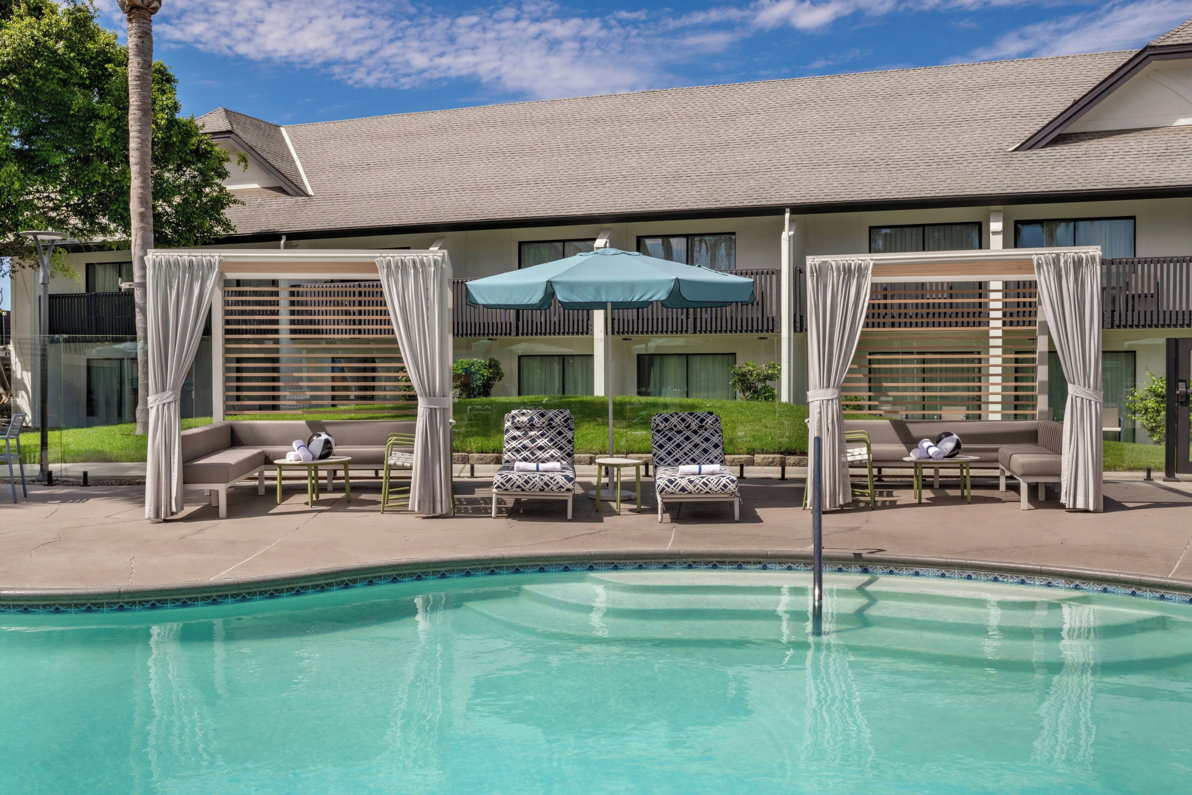 A pool area with lounge chairs, a table, and an umbrella.