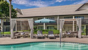 A pool area with lounge chairs, a table, and an umbrella.