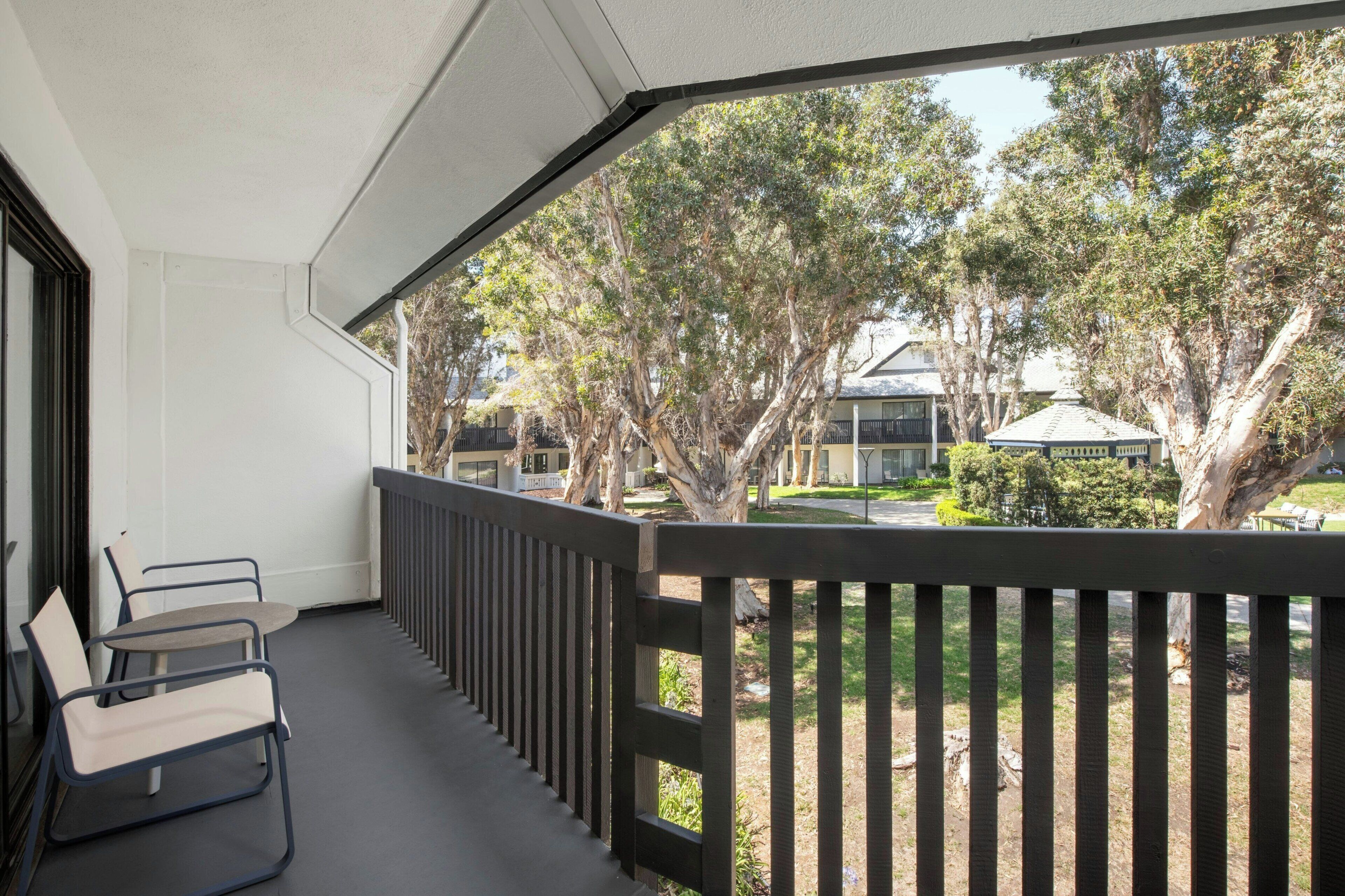 A balcony with a view of trees and a building in the background.