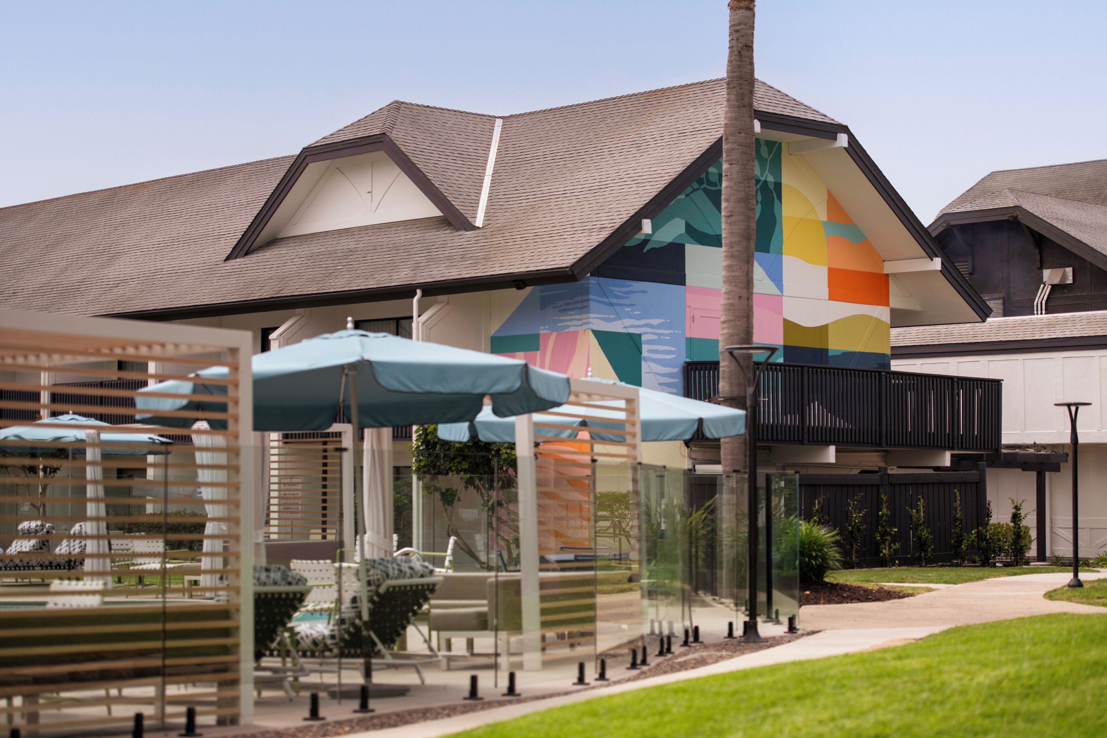 A hotel with a distinctive geometric facade, outdoor seating with umbrellas, and a well-maintained lawn.
