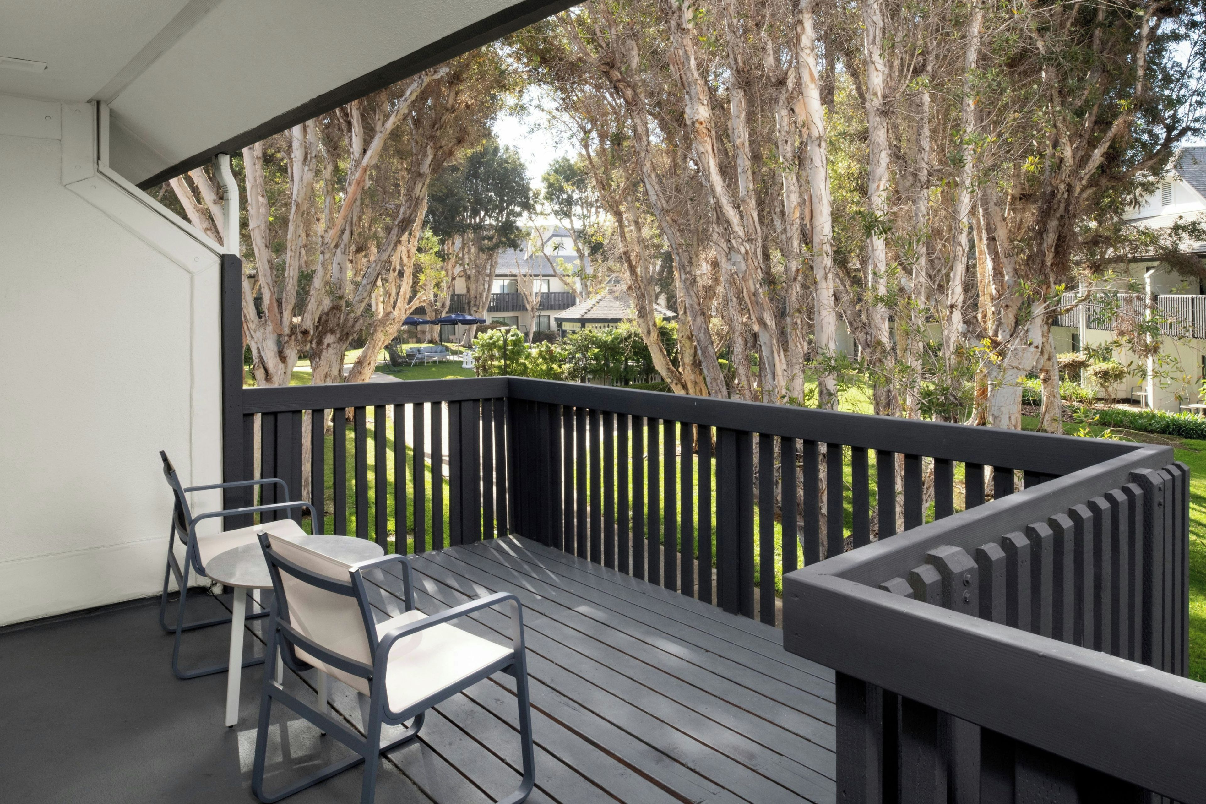 A balcony with a table and chairs, surrounded by trees and a view of a residential area.