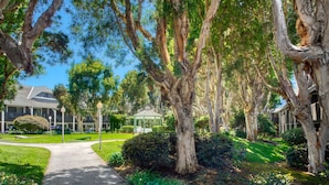 A pathway leading to a building with a covered gazebo, surrounded by mature trees and well-maintained lawns.