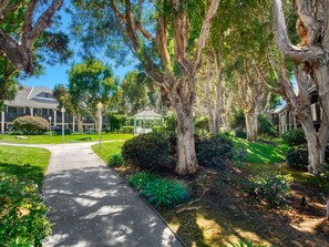 A pathway leading to a building with a covered gazebo, surrounded by mature trees and well-maintained lawns.