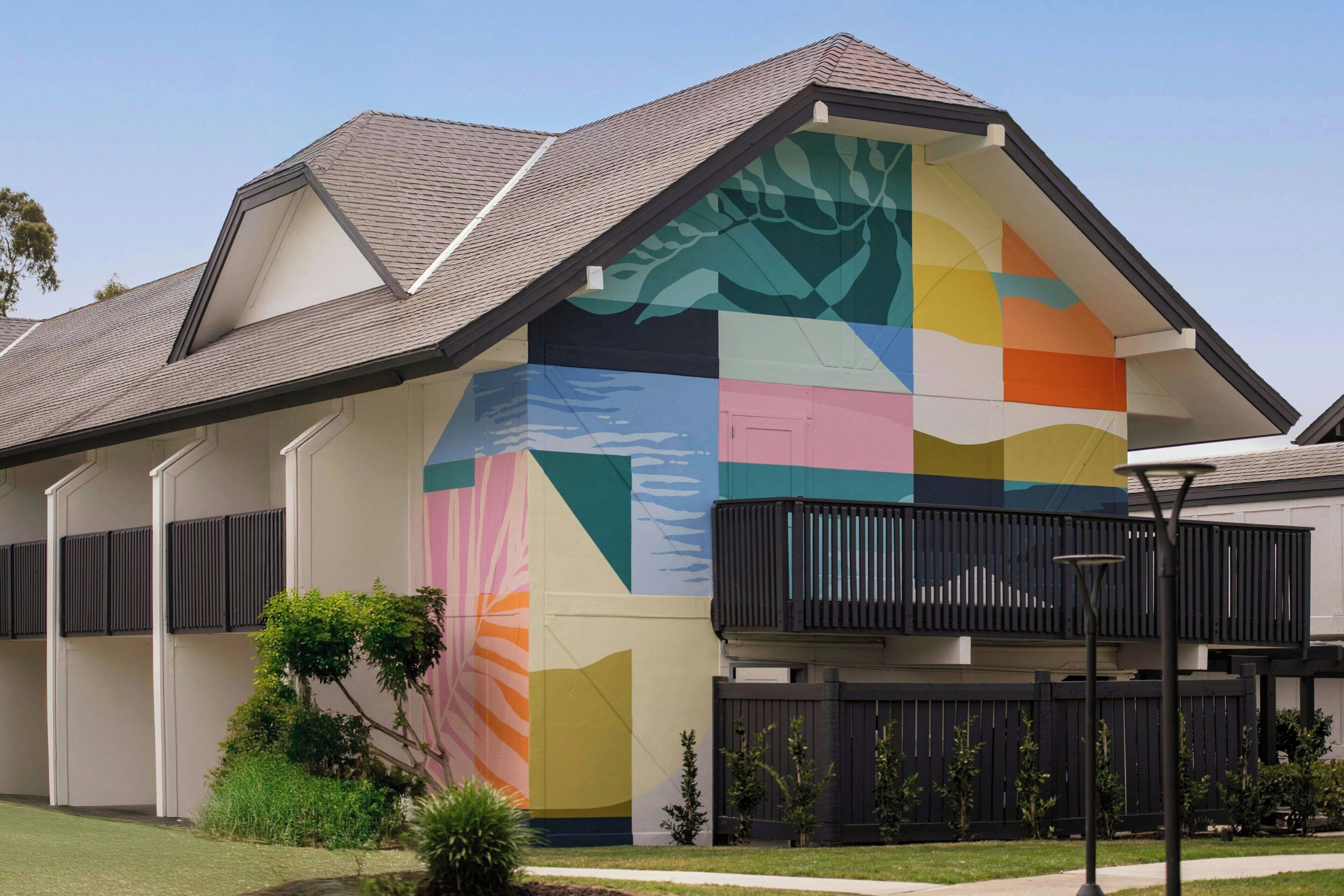 A house with a colorful exterior wall and a black balcony.
