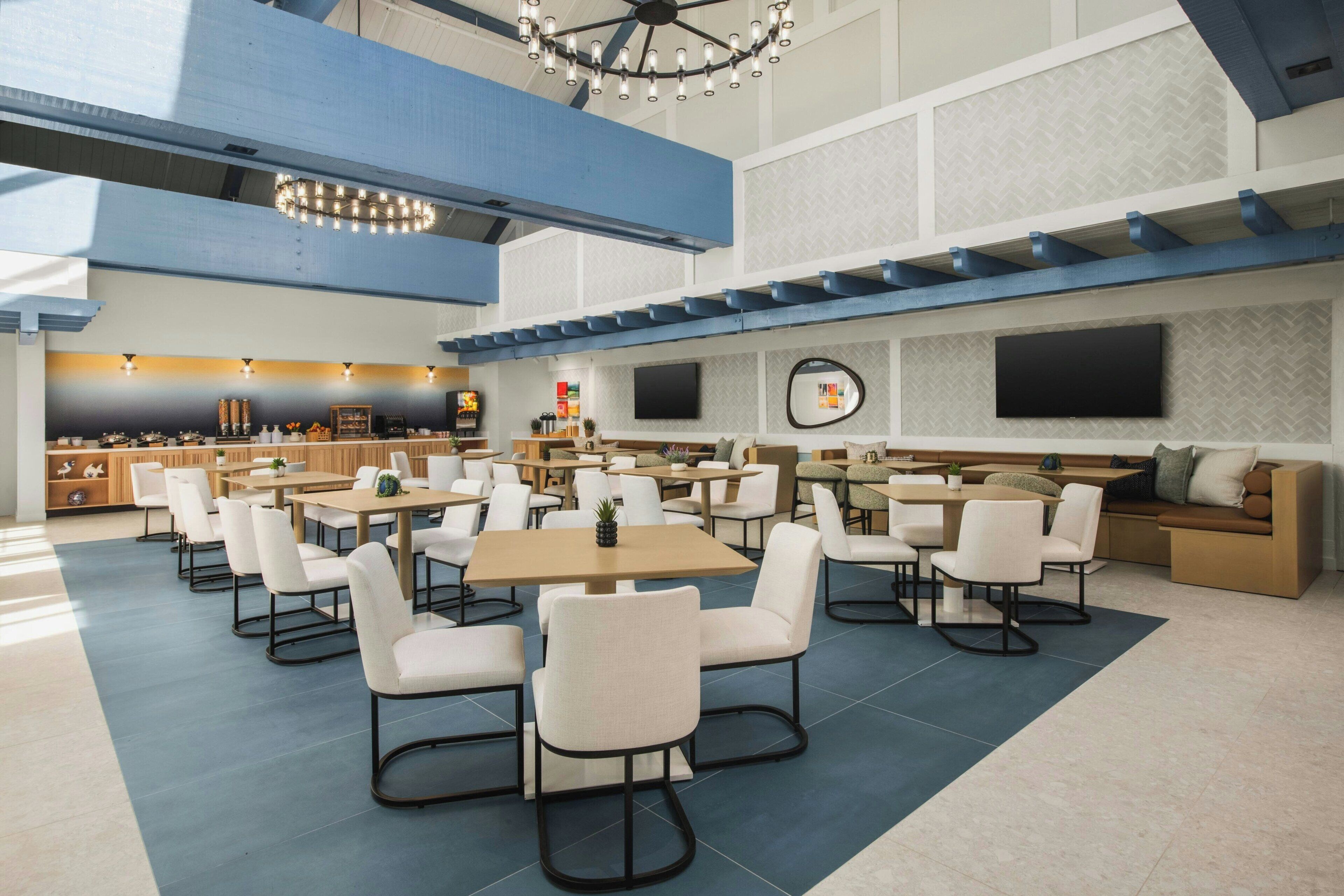 A spacious indoor area with multiple seating arrangements, including tables and chairs, and a bar area with various items on display.