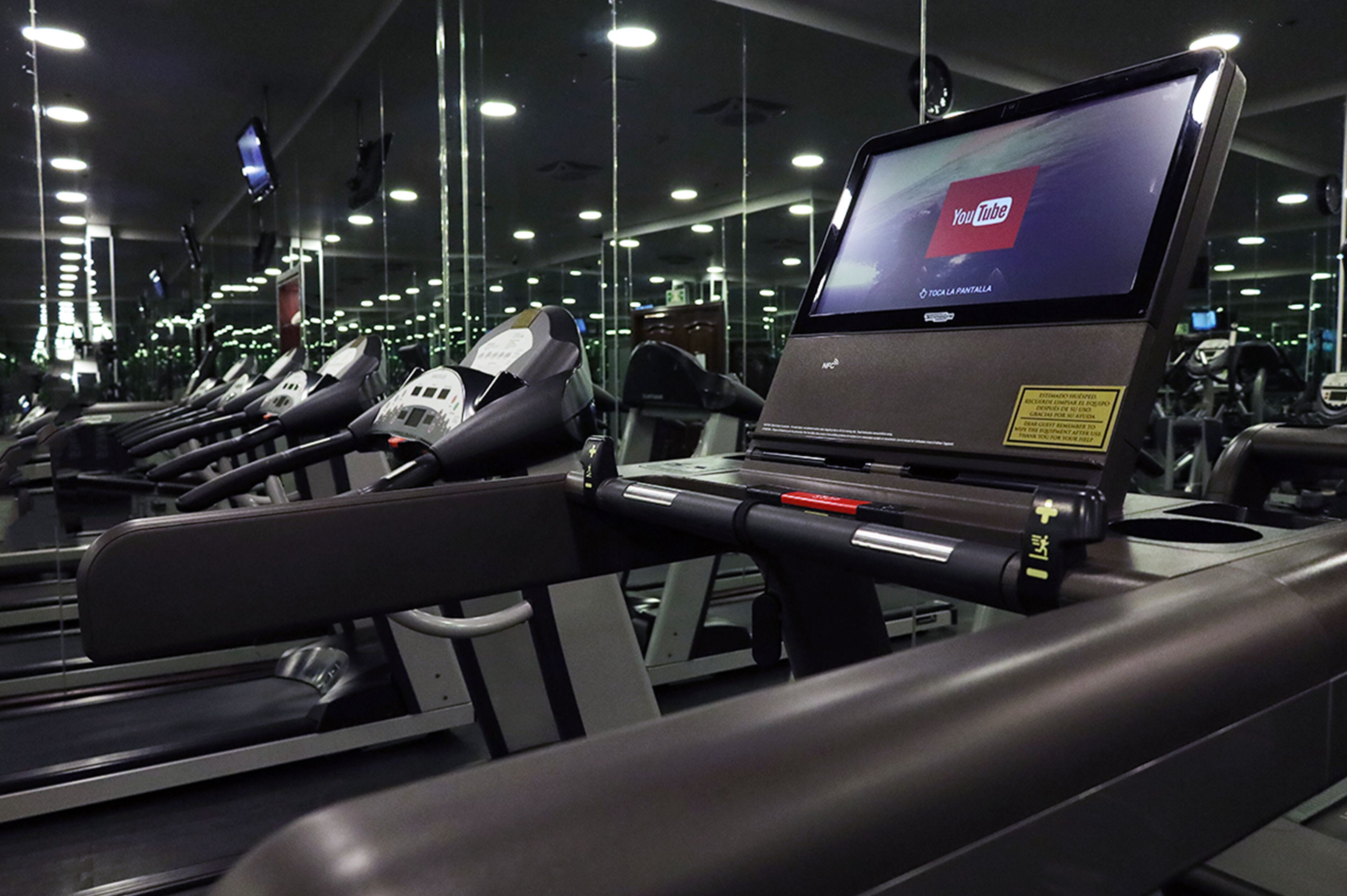 A gym with treadmills and a laptop displaying a YouTube logo.