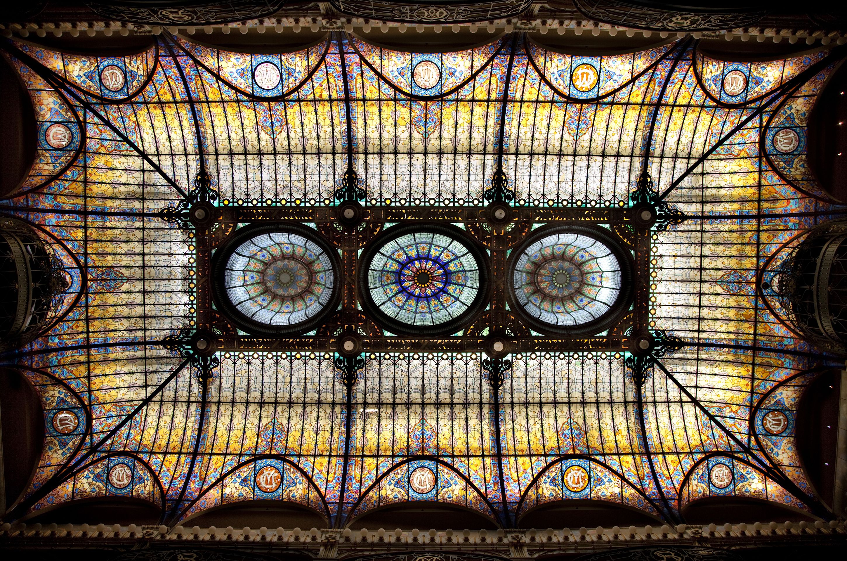 A stained glass window with intricate designs and three circular medallions.