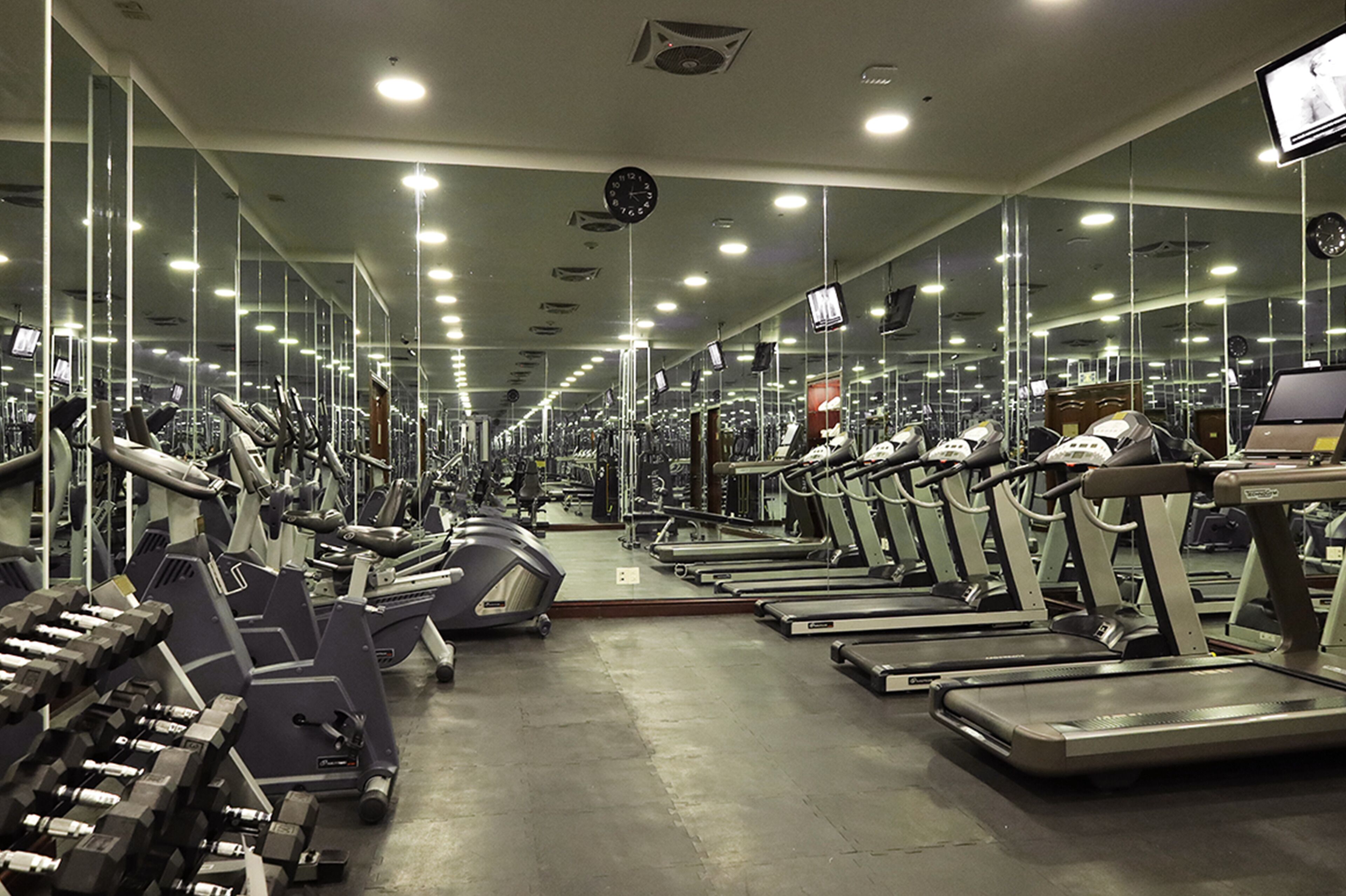 A gym with treadmills, dumbbells, and weight machines.