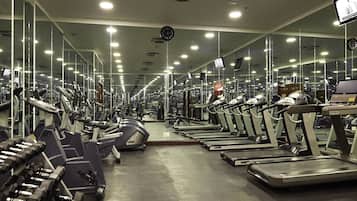 Un gimnasio con cintas de correr, mancuernas y máquinas de pesas.