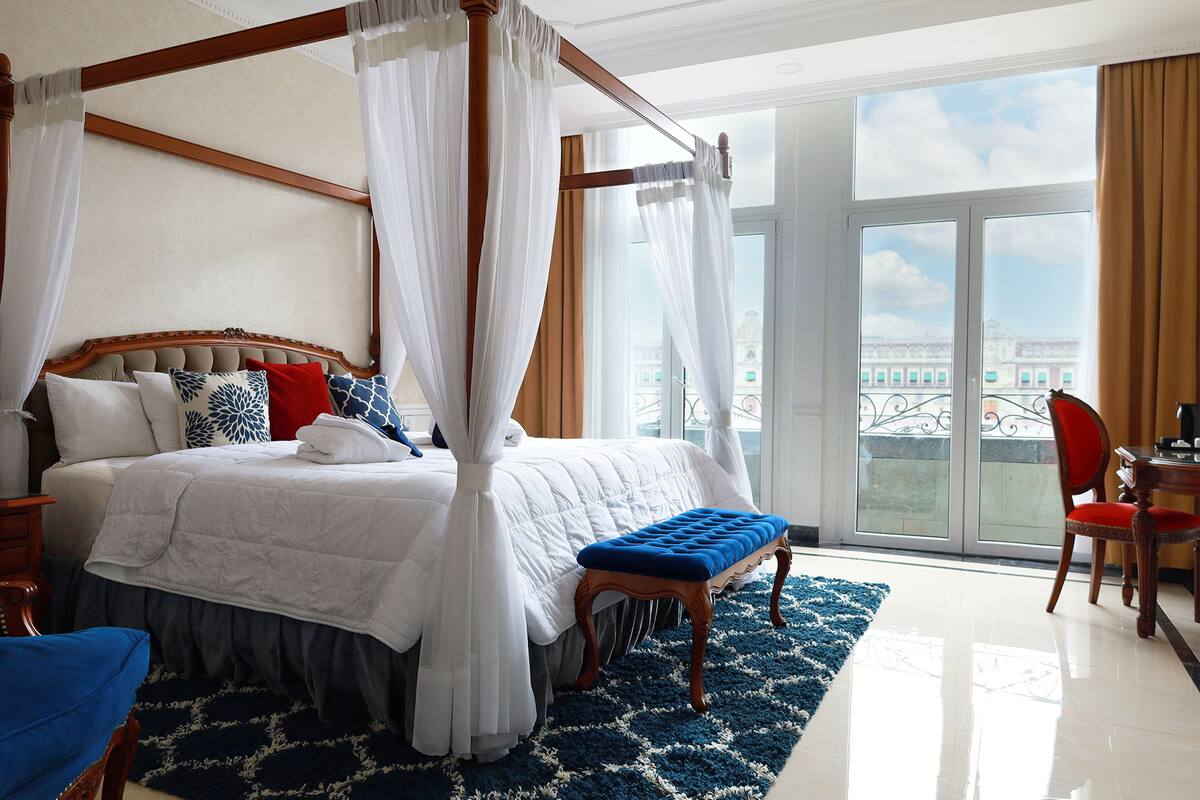 A four-poster canopy bed with a view of the city through large windows.