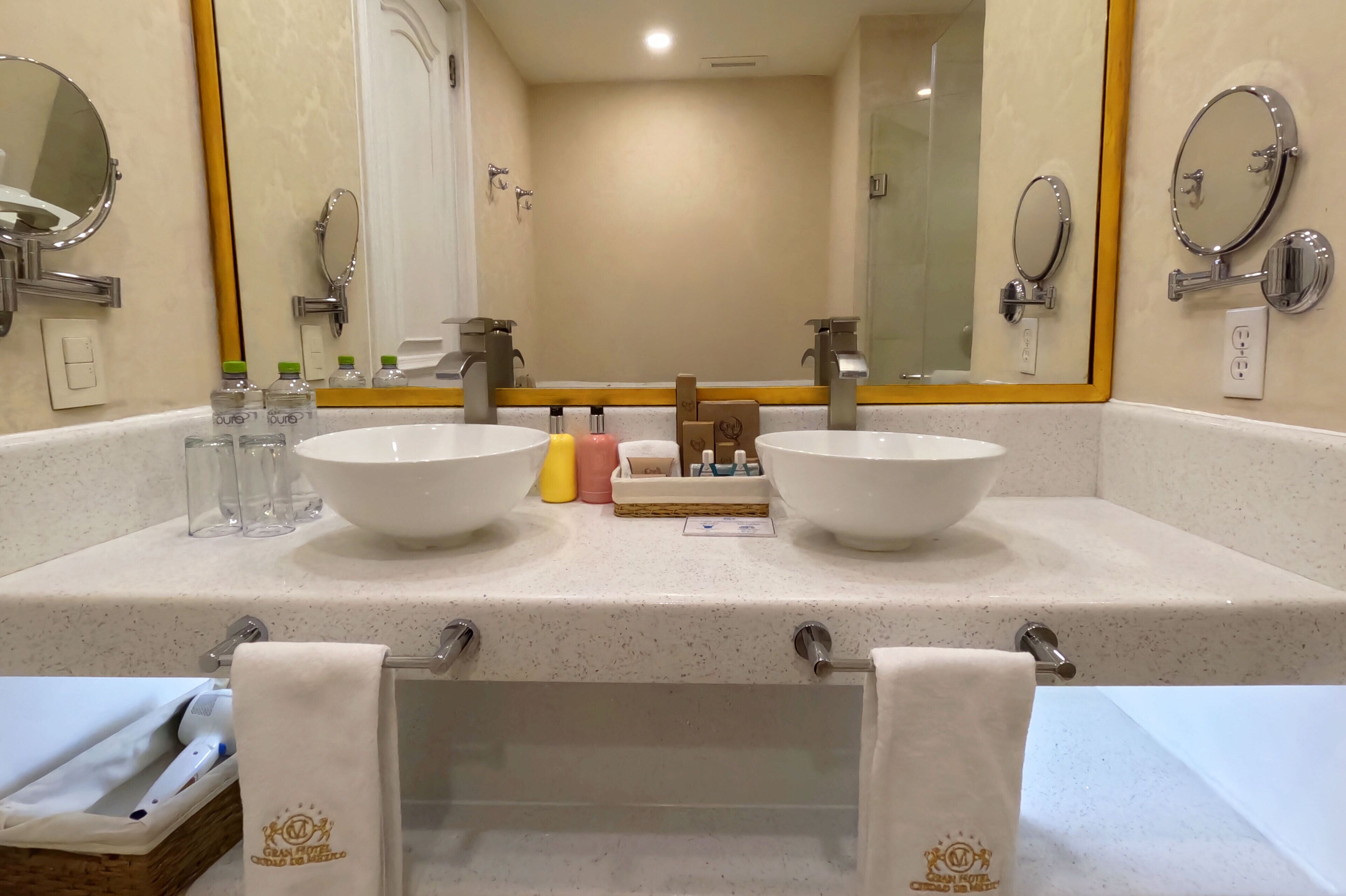 Un baño de hotel con dos lavamanos, un espejo grande y un perchero para toallas.