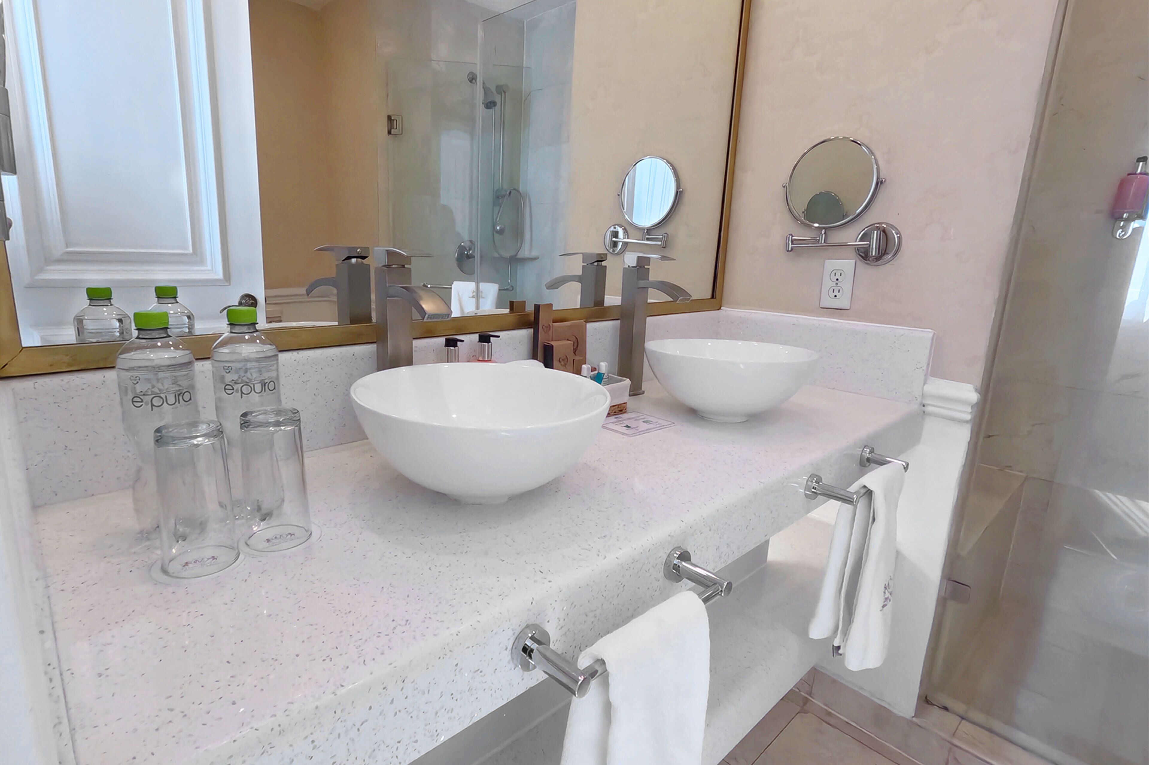 Une salle de bain avec deux lavabos, un grand miroir et une douche à parois de verre.