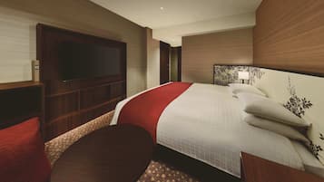 Une chambre d’hôtel avec un grand lit, un téléviseur à écran plat, une petite table ronde et une chaise rouge.