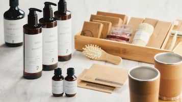 A variety of personal care products including shampoos, body lotions, and a personal skincare kit, arranged on a marble surface.