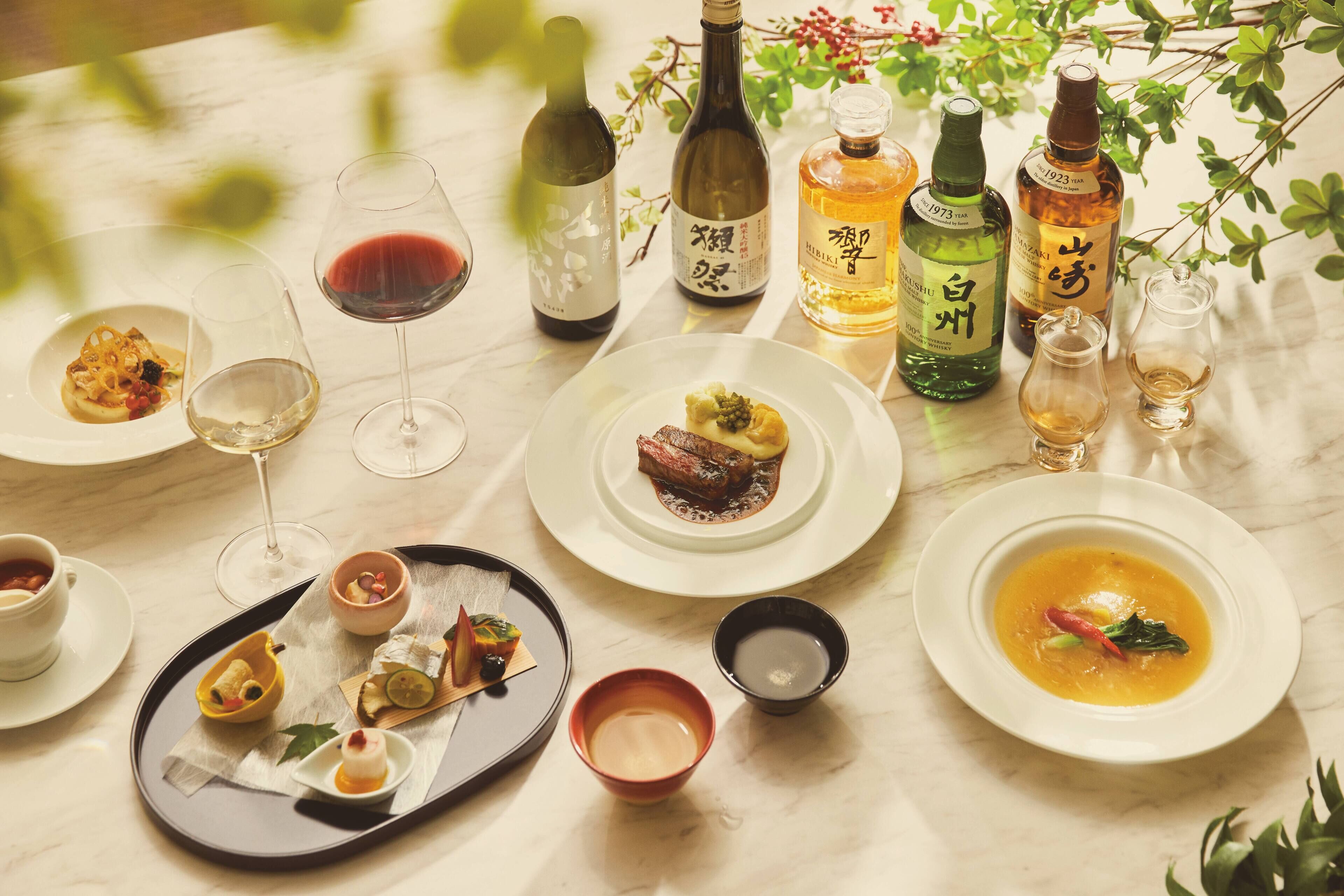 A table set with various dishes, glasses of wine, and bottles of liquor.