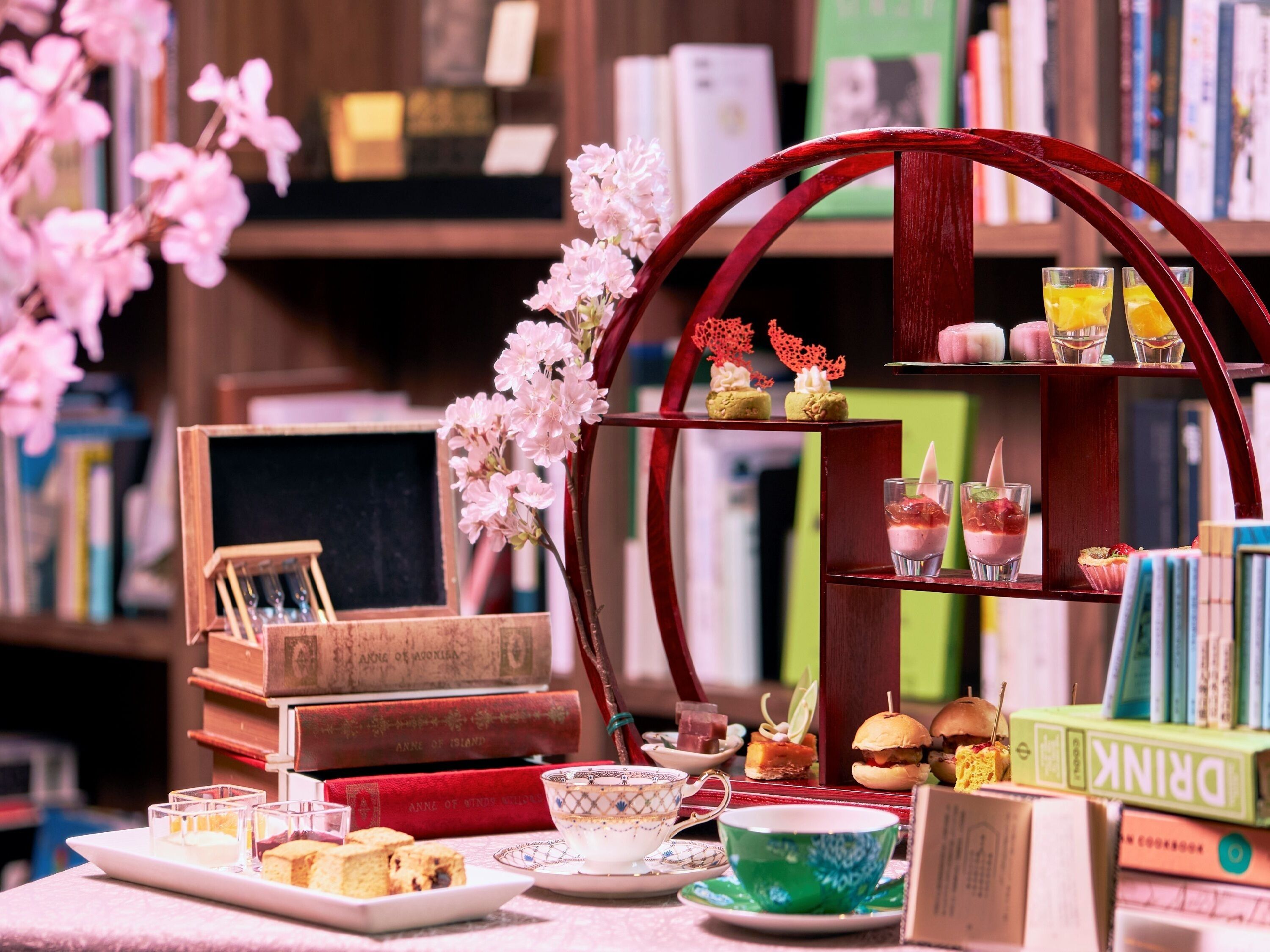 A tea setting with a teapot, cups, and a tray of pastries.