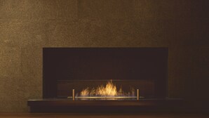 A fireplace with a fire burning inside, set against a textured wall. - Shiba Park Hotel (Tokyo)