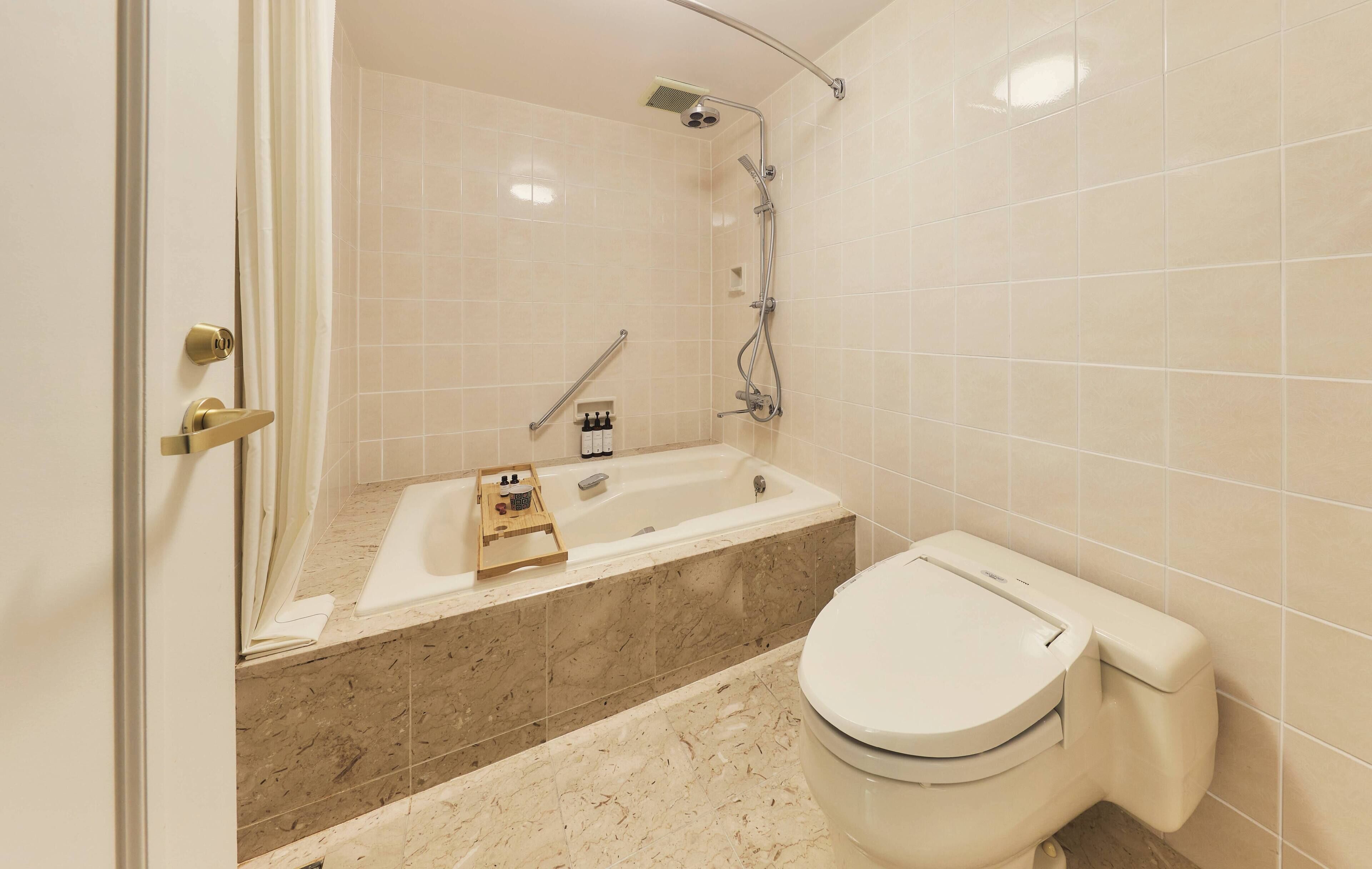 A bathroom with a bathtub, shower, and toilet.