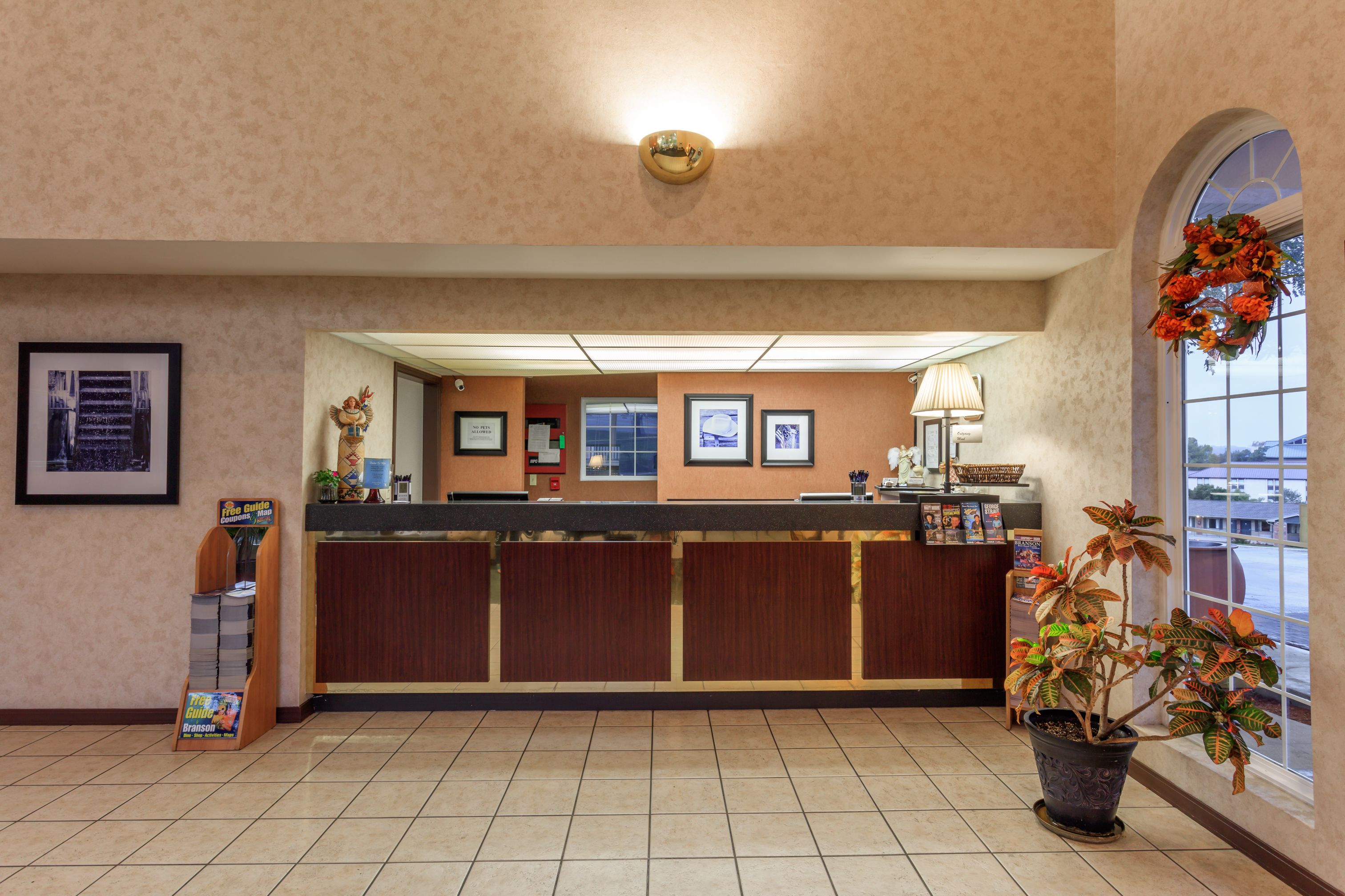 A reception area with a counter, framed pictures, a potted plant, and a signboard.