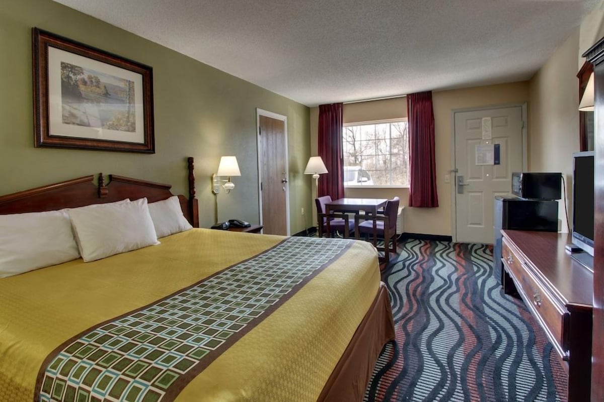 Een hotelkamer met een bed, een bureau, een stoel, een televisie en een kamerbreed tapijt met een patroon.