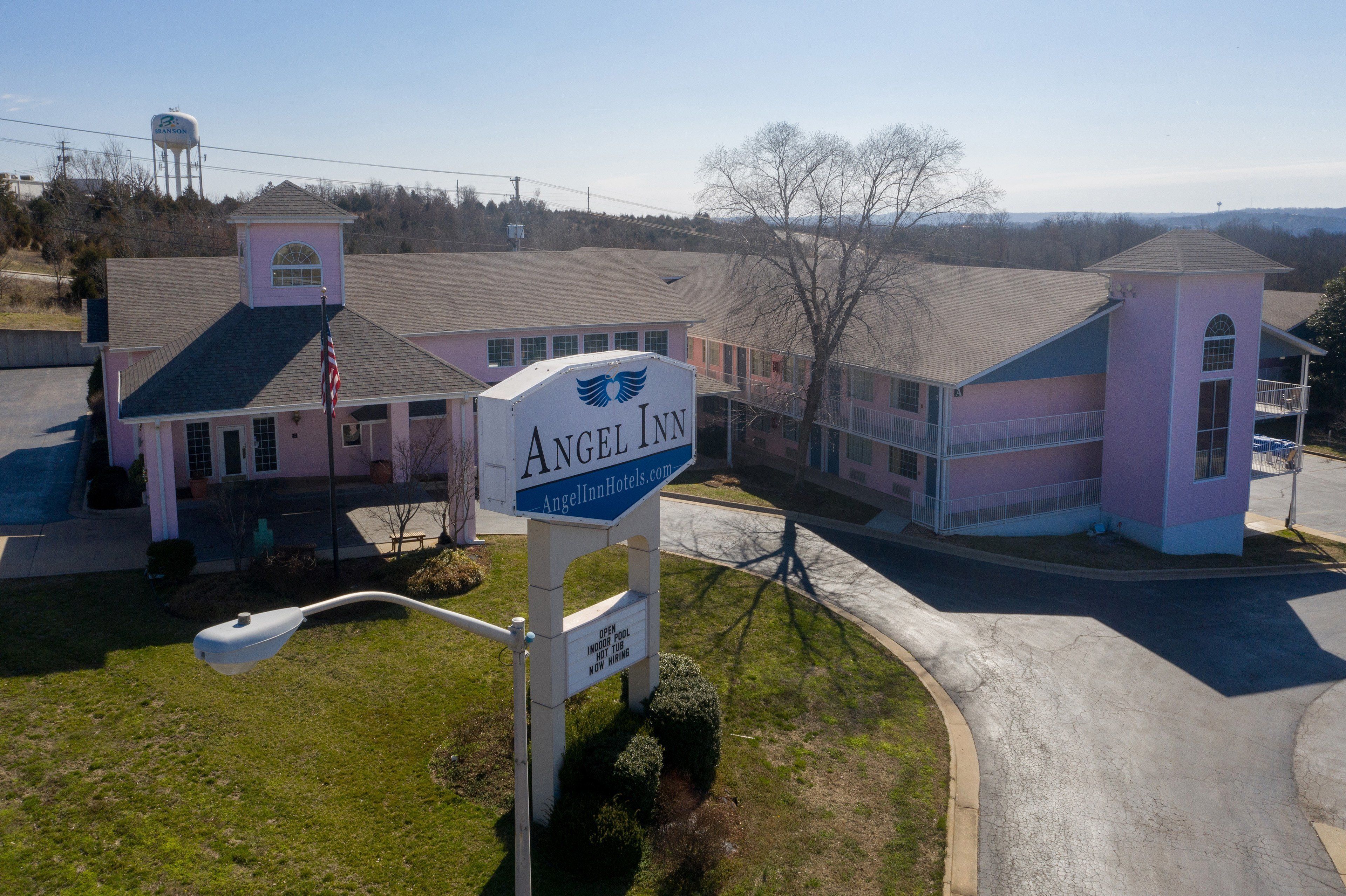 A hotel with a prominent sign, a water tower in the background, and a clear sky.