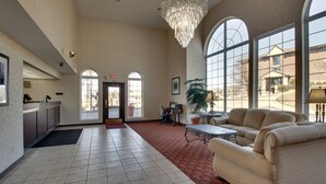A spacious lobby with a red carpet, a chandelier, a reception desk, and a seating area with sofas. - Angel Inn Central (Branson)