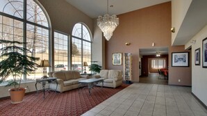 A spacious living area with large windows, a chandelier, and a red patterned carpet. - Angel Inn Central (Branson)