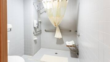 A wheelchair-accessible shower with a grab bar, a handheld showerhead, and a towel rack.