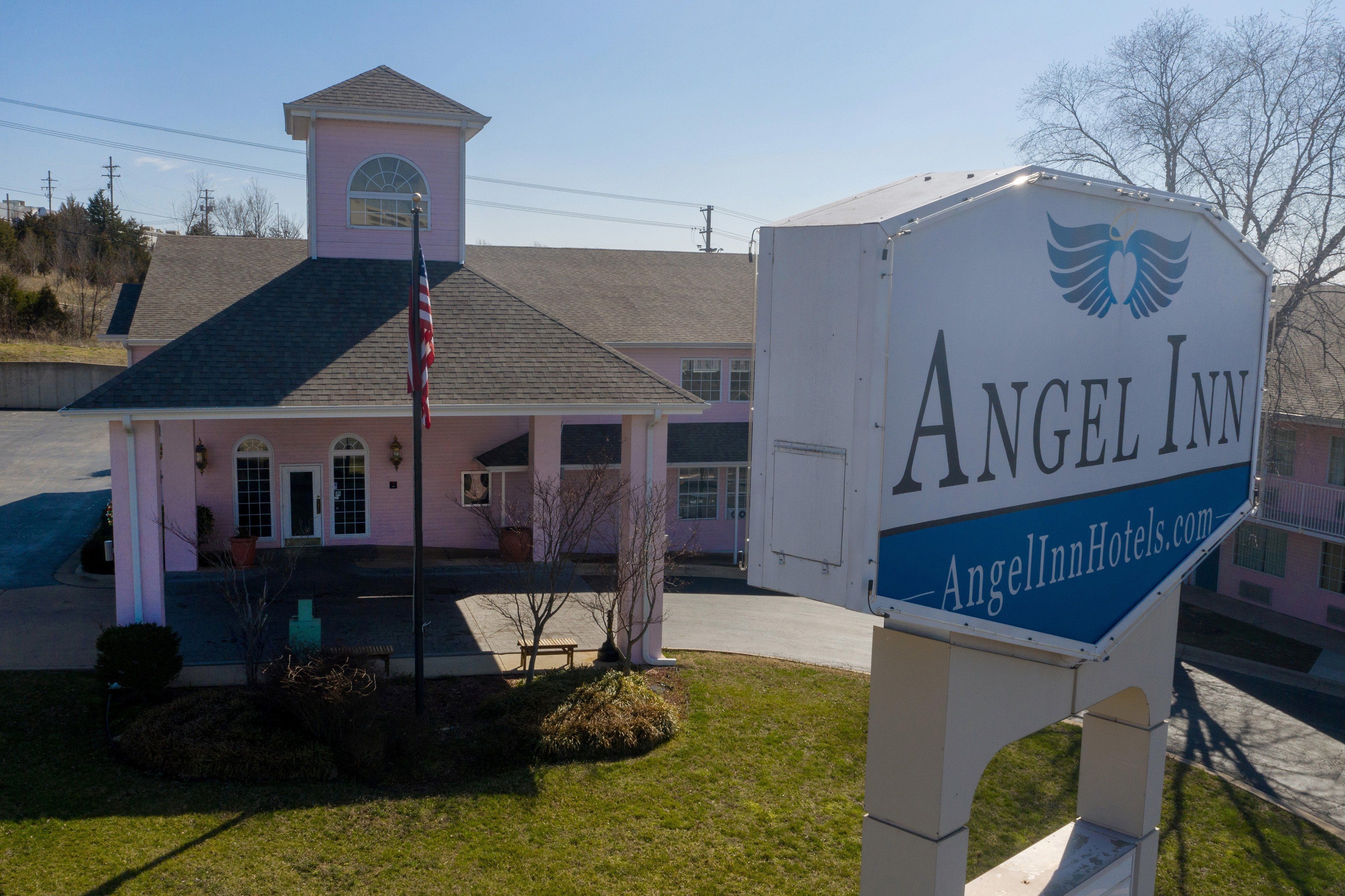 A hotel named Angel Inn with a prominent sign, a small tower-like structure, and a well-maintained lawn.