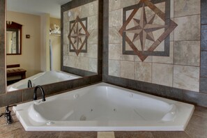 A modern bathroom with a large freestanding bathtub, a mirror, and decorative wall tiles.
