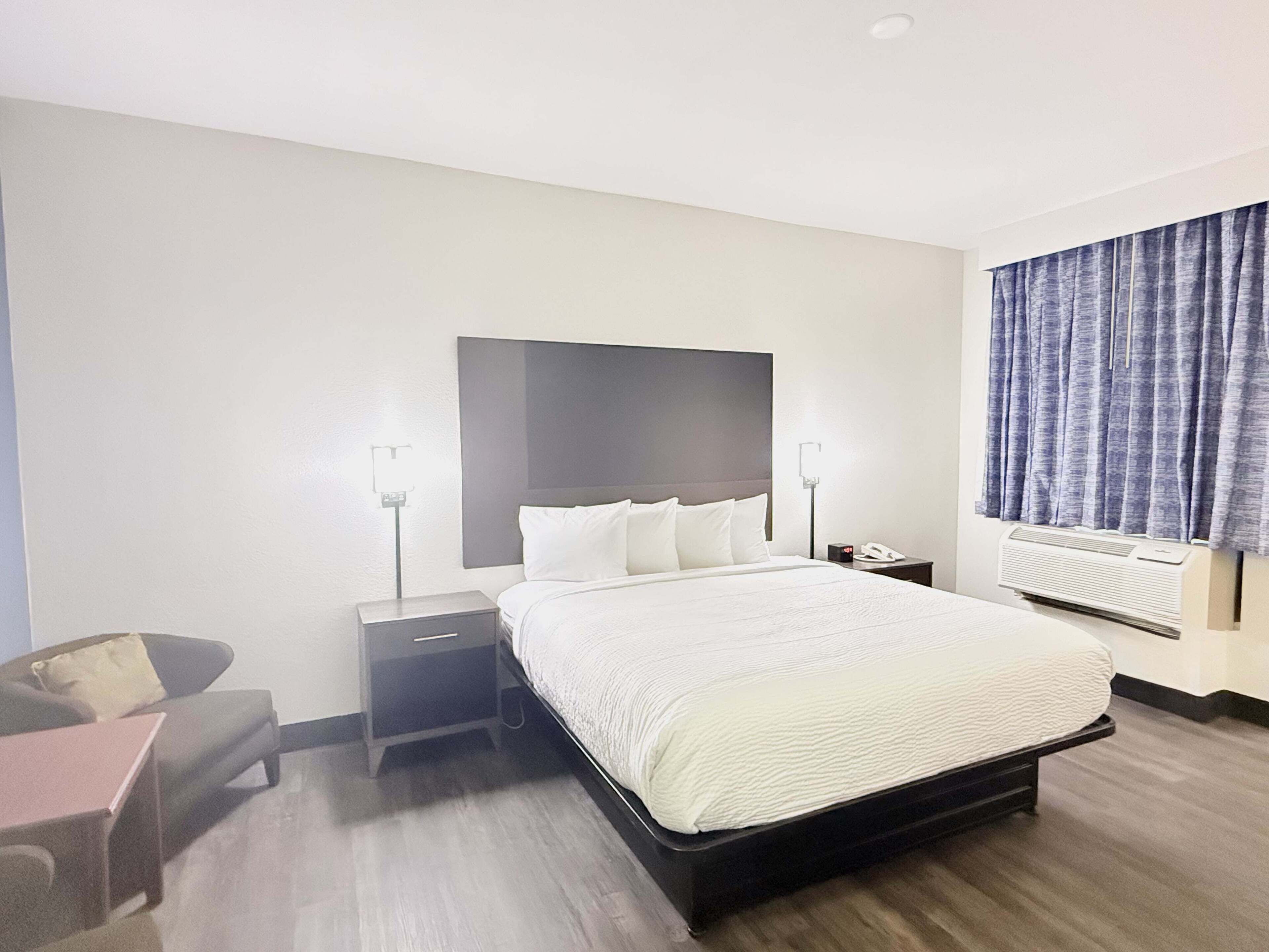 Une chambre d’hôtel avec un grand lit, des tables de chevet, un bureau et une chaise.