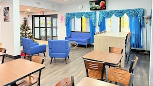 A dining area with blue sofas, wooden tables, and blue curtains.
