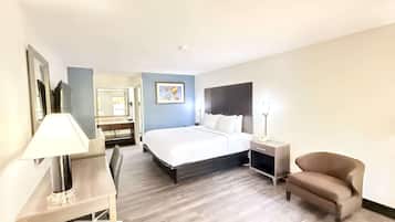 A hotel room with a large bed, bedside tables, a desk, a chair, and a bathroom visible through an open door.