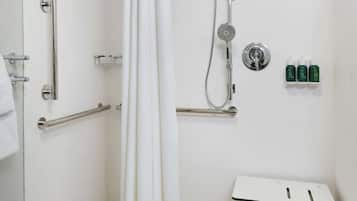 A shower area with a white curtain, grab bars, a handheld showerhead, and a small table.